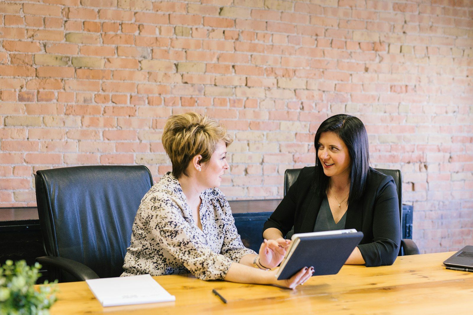 Two professionals reviewing work on a tablet in a meeting room