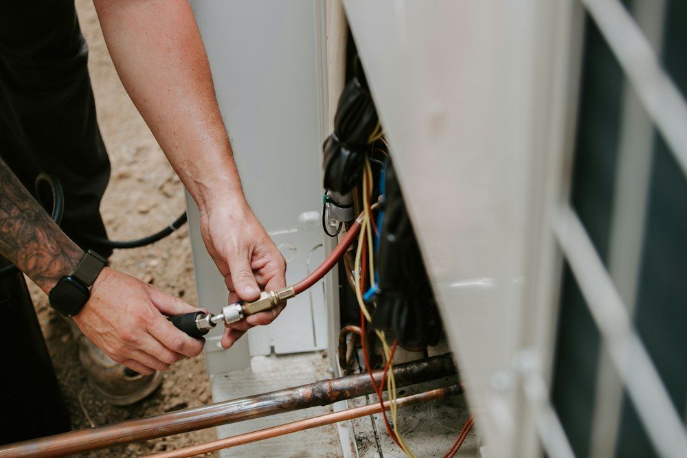 A technician servicing an outdoor air conditioning unit