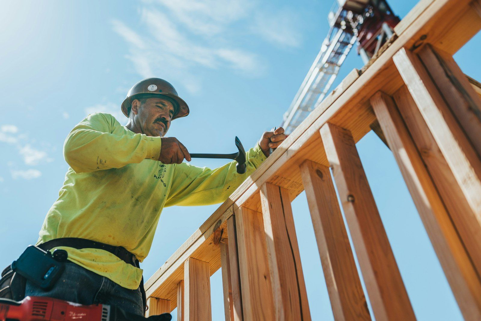 A builder in a hard hat framing a timber structure