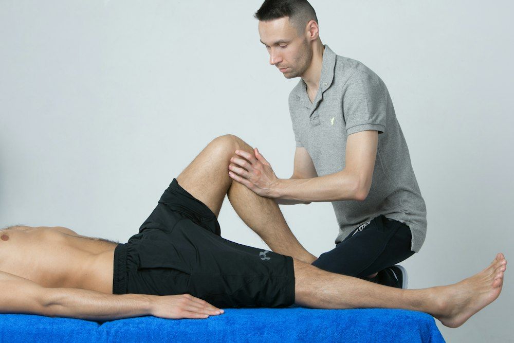 A practitioner assessing a patient’s knee on a treatment table