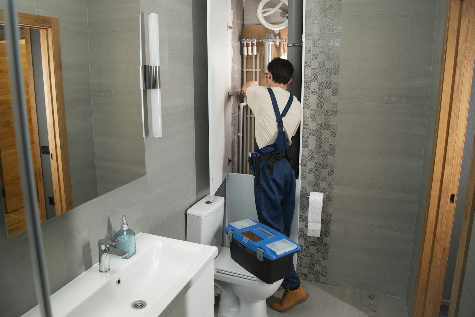 A plumber working on pipes in a modern bathroom